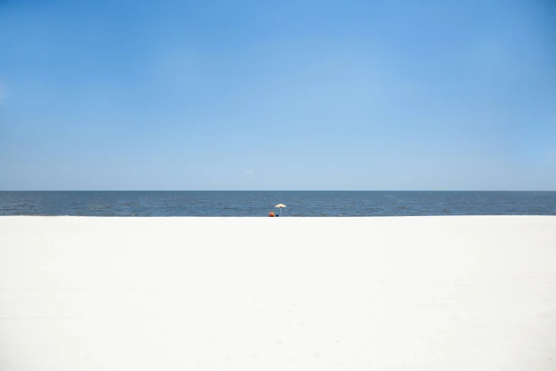 a white sandy beach with a lone boat in the distance