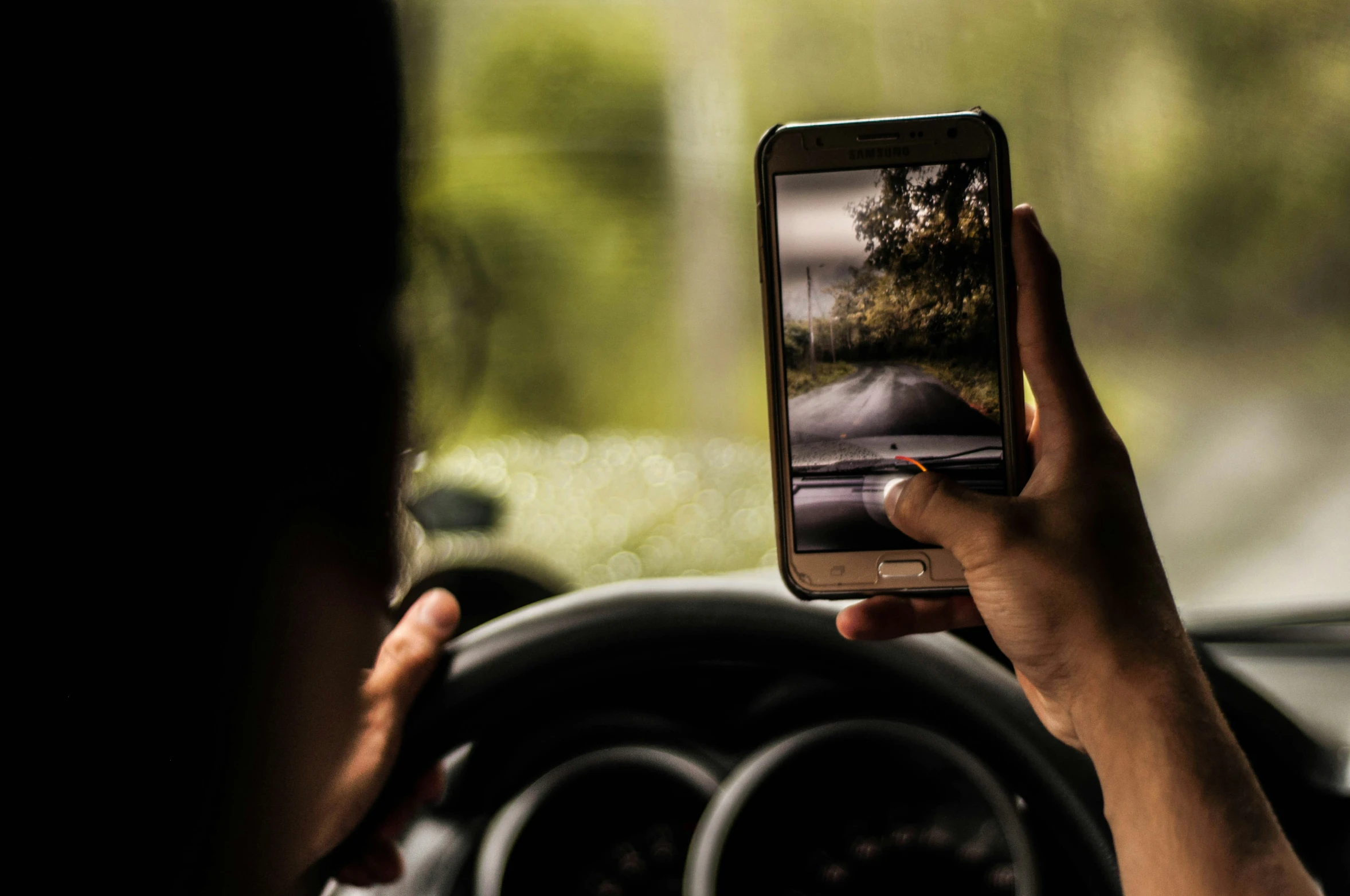 a woman holding her phone in the back of a car