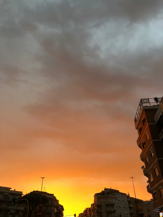 a sunset with the sun behind buildings