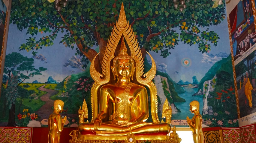 gold statue in front of mural depicting buddha