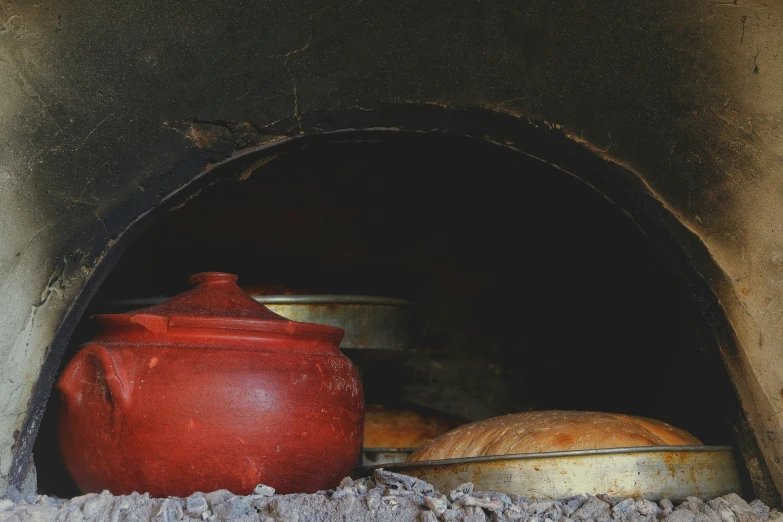 a red pot and a bowl sitting in an old stone oven