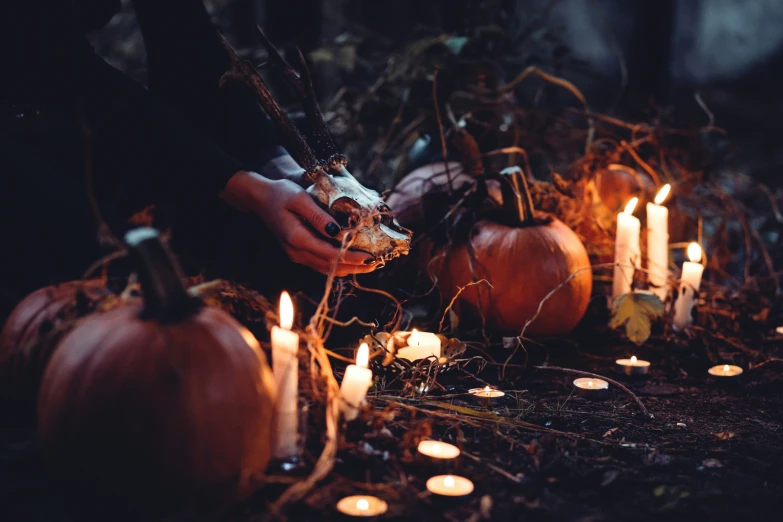 someone lighting candles in front of pumpkins