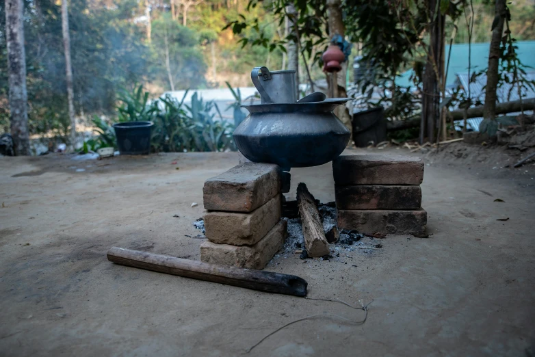 an outdoor cooking area with some pots, a shovel and some wood