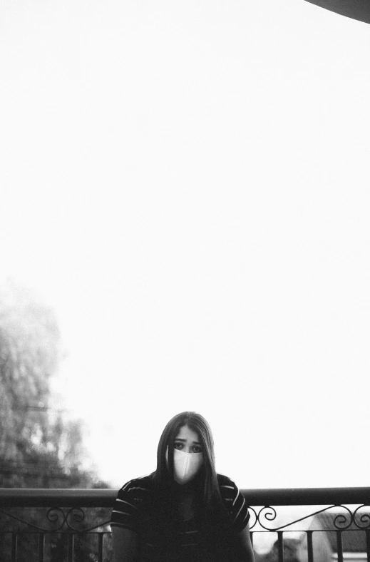 woman wearing black coat sitting on a metal fence