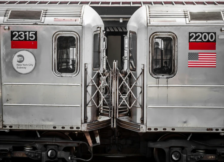 two silver trains with large doors sitting side by side