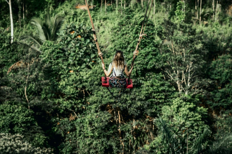 the woman is riding on a swing set with two ropes