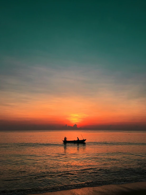 the sun is rising over an ocean with two boats