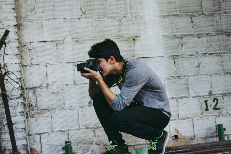 a man squatting on the ground taking a picture