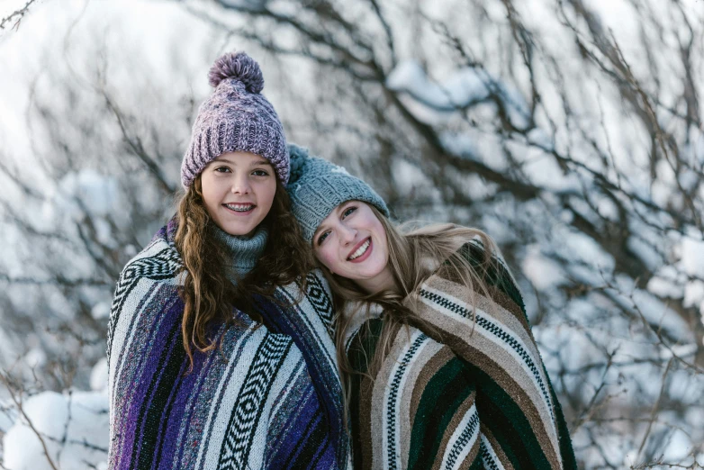 two women are posing with a blanket in the snow