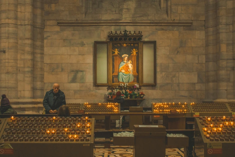 a group of people sitting next to a church with candles