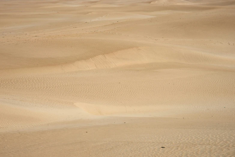 a man riding a surfboard over sand dunes