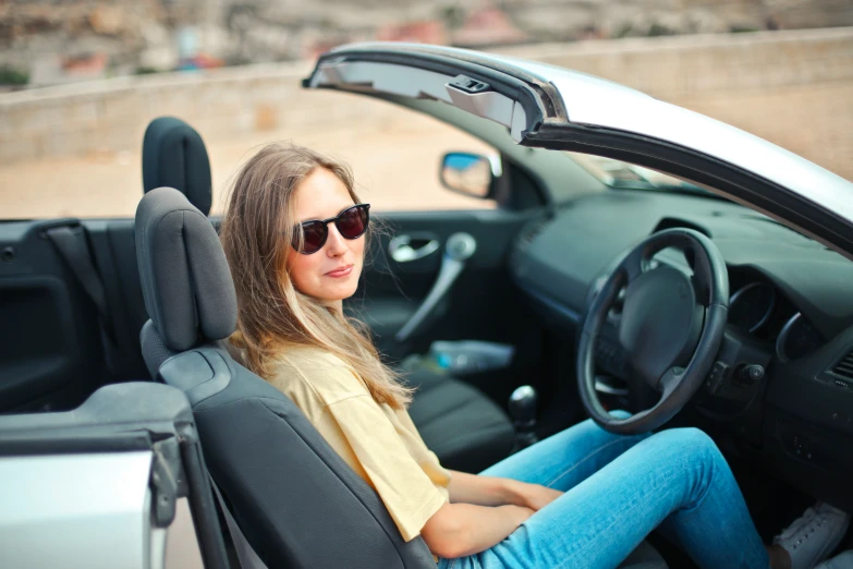 a woman with glasses sits in her car