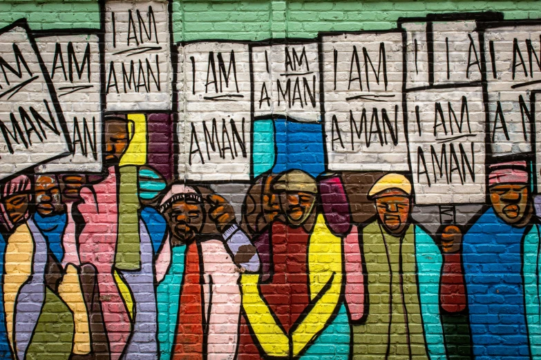 some people walking by a brick wall with signs on it