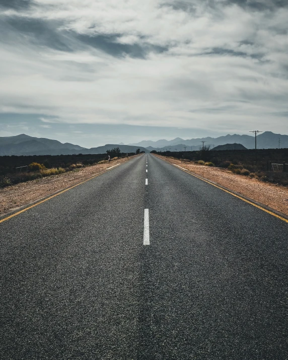 a road with a lone sign and some mountains in the distance