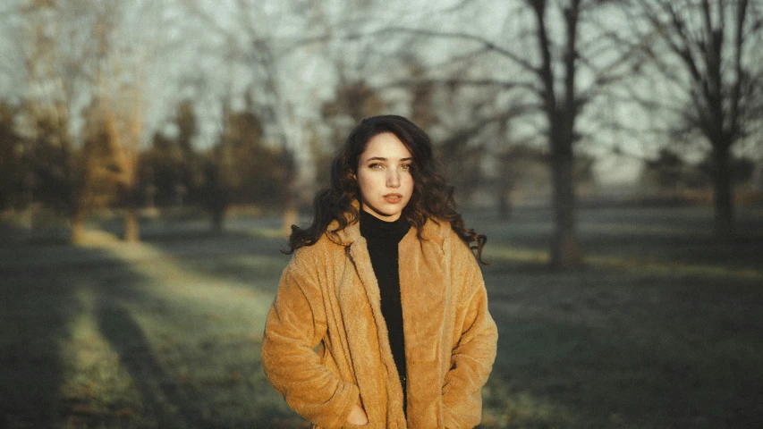 a woman is standing outside in the fall and looking to her left