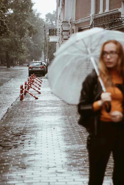 a woman holding an umbrella walks down the street