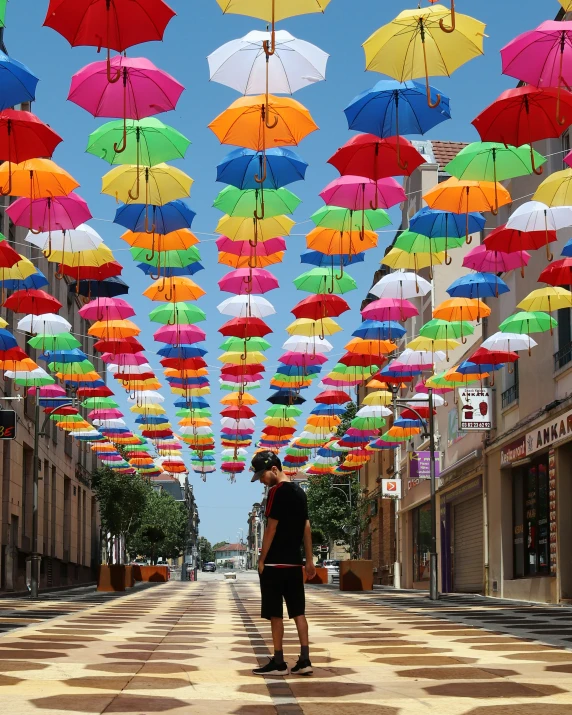 a  looks up at many umbrellas hung above him