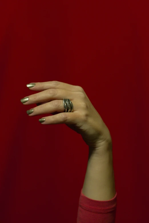 someone with long, shiny nails with two rings on their finger