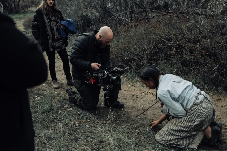 a man squats in front of a camera while a pographer takes pictures