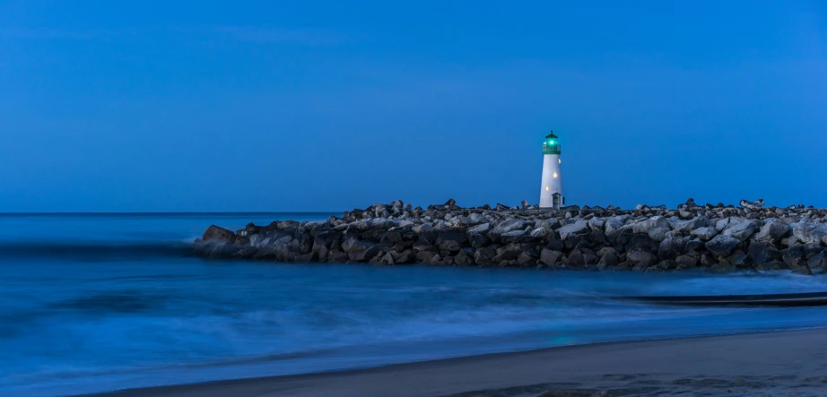 a white and green light house sitting next to the ocean