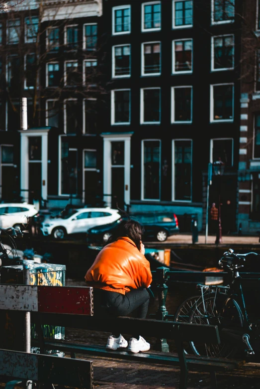 a woman with an orange jacket kneeling by some bicycles