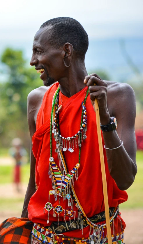 a man wearing bright clothes and holding a yellow stick