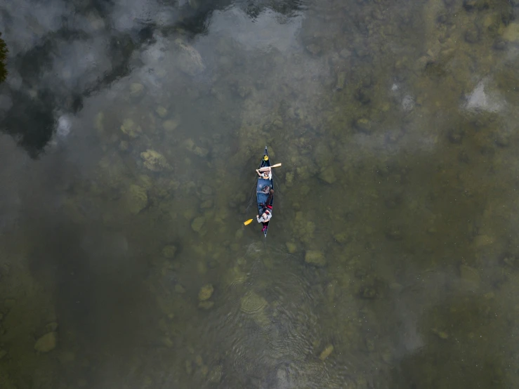 an aerial view of a person on a kayak in shallow water