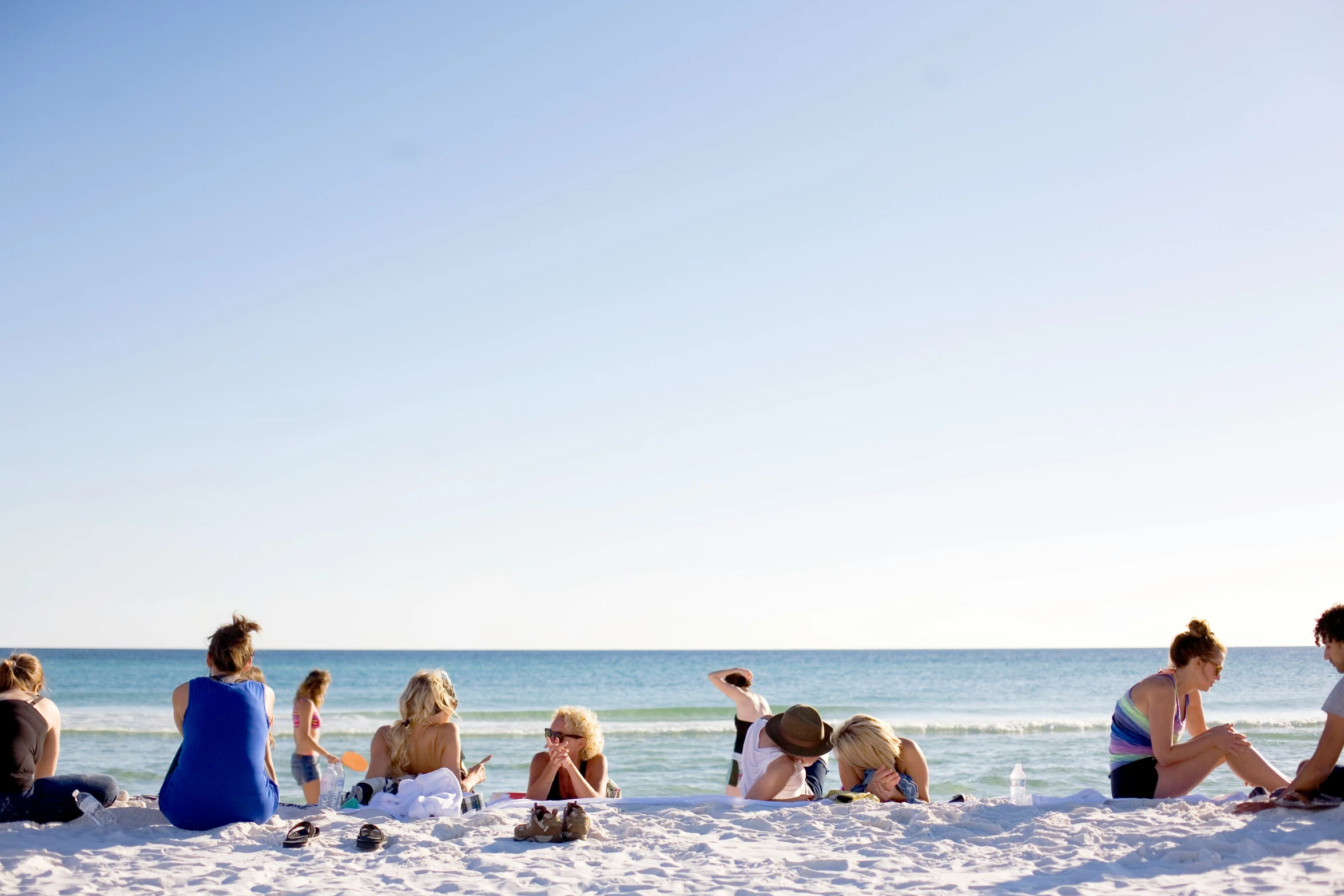 several people sitting on the sand at a beach