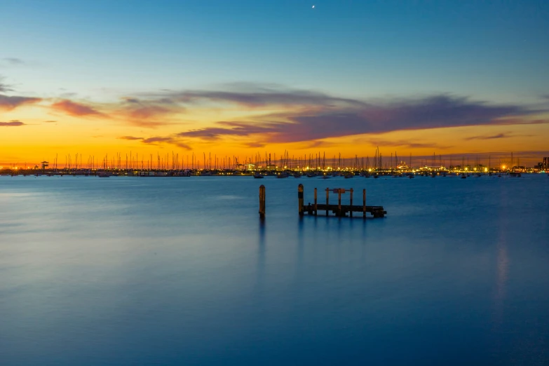 boats in a harbor at sunset under an orange and blue sky