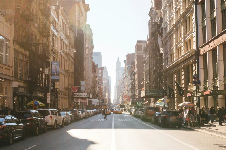 a street with people walking and cars parked on the sides