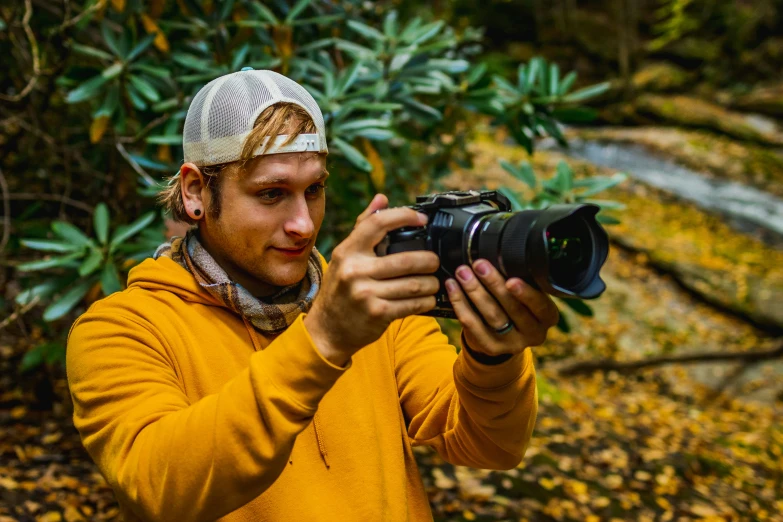 a man standing near a bush taking a picture with a camera