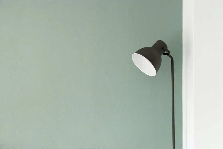 a lamp is on the wall in front of green painted walls
