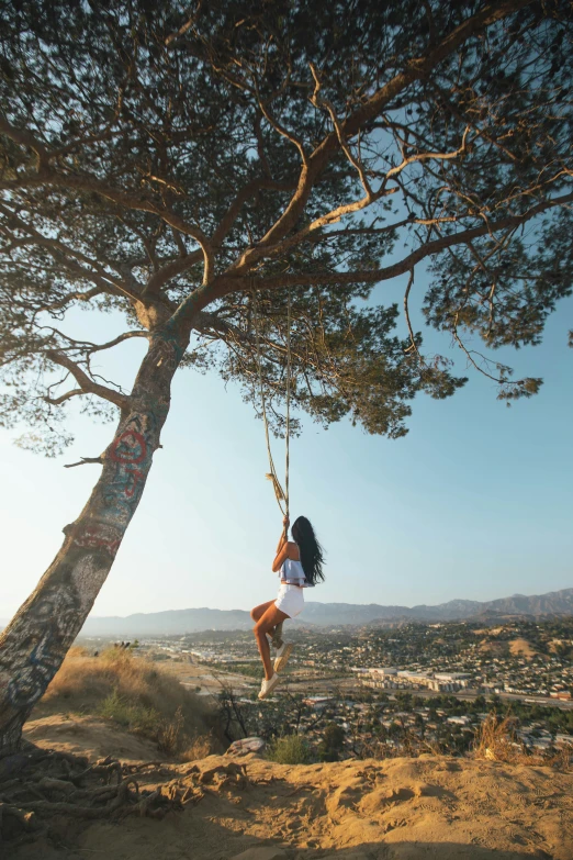 the woman is climbing on the tree and looking down