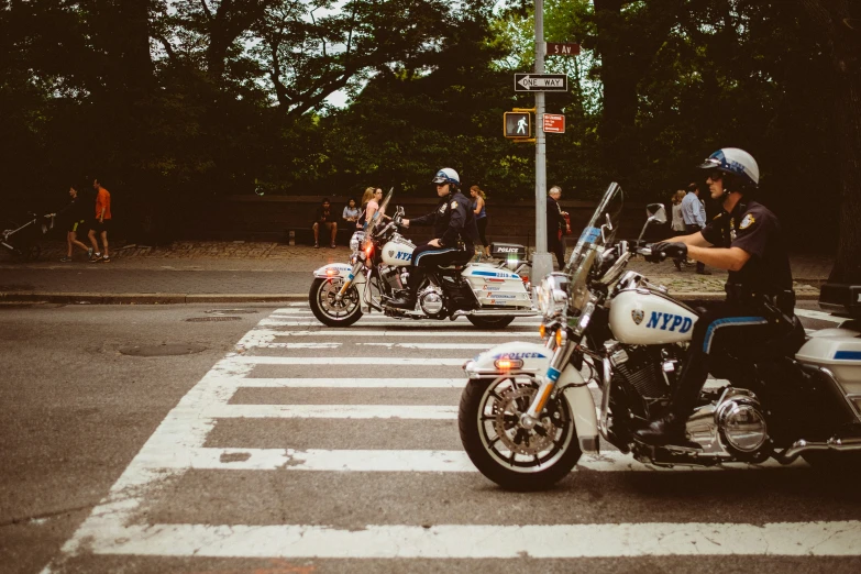 police officers on motorcycles wait to cross the street