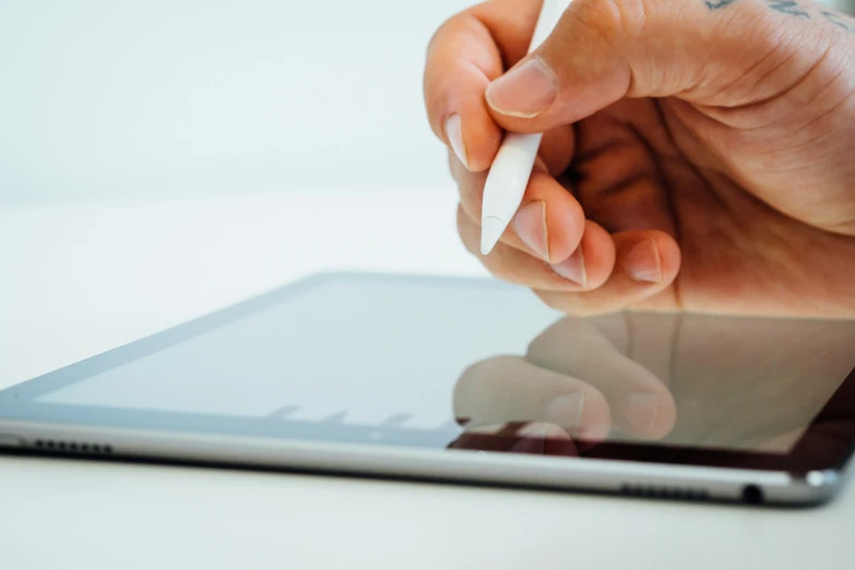 a person holding a pen while touching their tablet