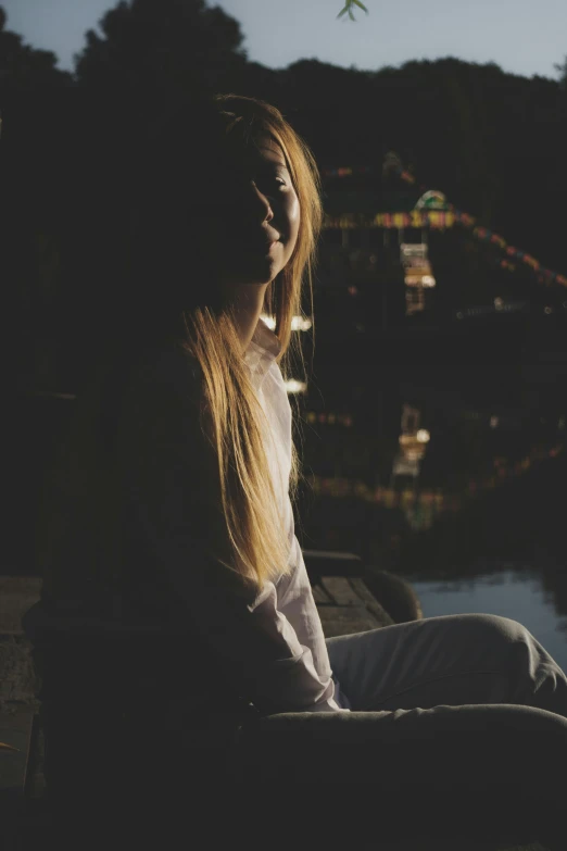 a woman sitting by the water looking at her cellphone