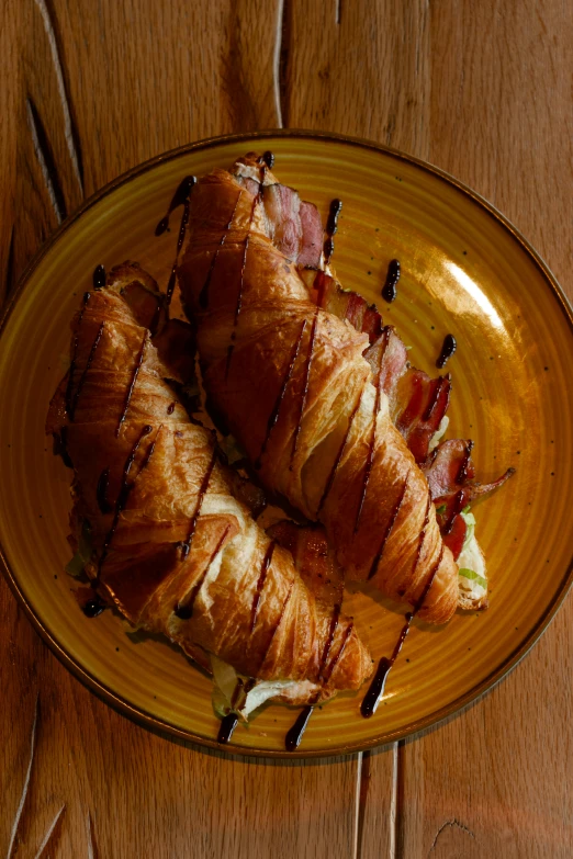 two bacon wrapped in strips of bread on a yellow plate