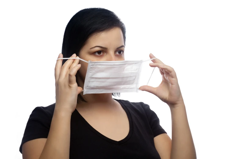 a young woman is using a medical mask on her face