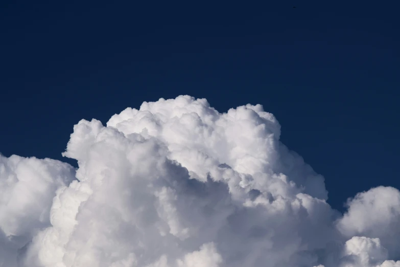 a big cloud of white clouds with a plane flying in the sky