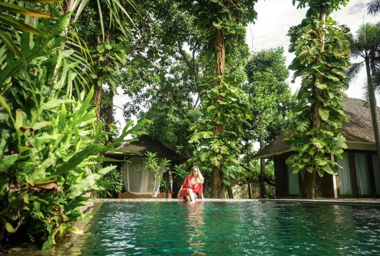 a woman is sitting at the end of an outdoor pool