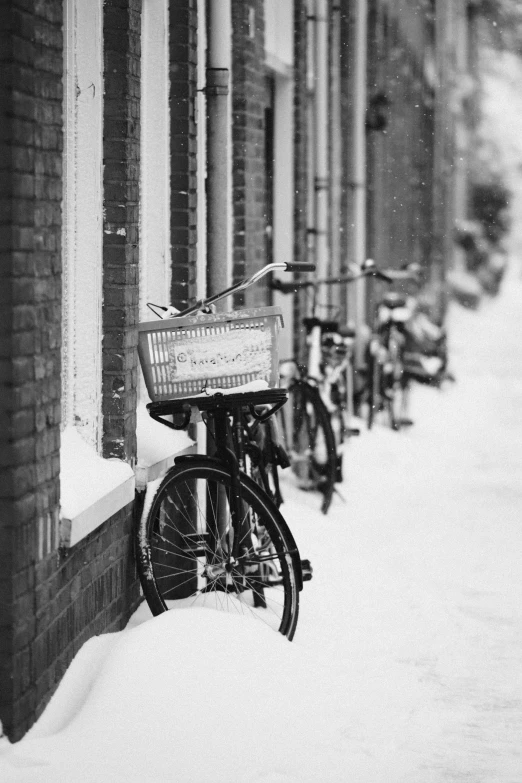 two bicycles are leaning against a wall and a basket sits outside