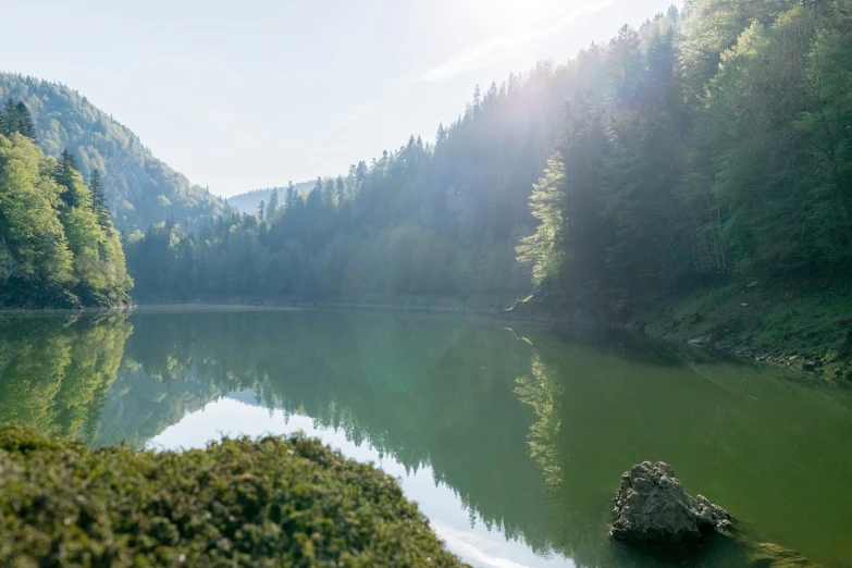 the sun shines brightly on a mountain lake