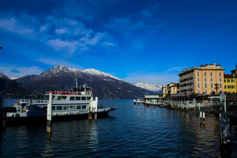 a large boat traveling down a river with buildings and mountains in the background