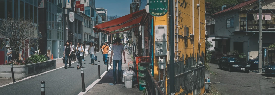 a view of people walking down the sidewalk on a narrow street