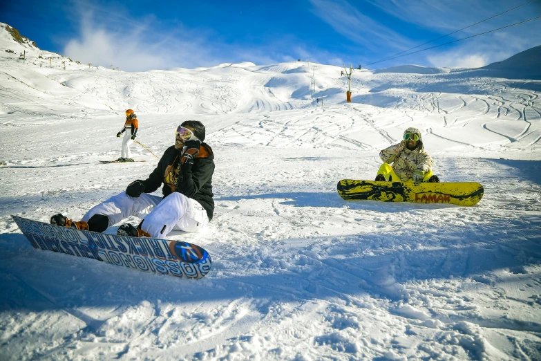 three snowboarders sitting in the snow on the slopes