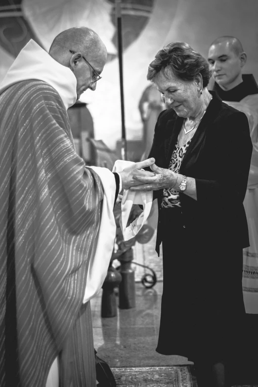 black and white pograph of a nun handing soing to a woman