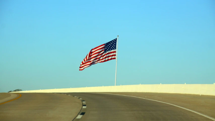 an american flag waves in the wind on a desert highway