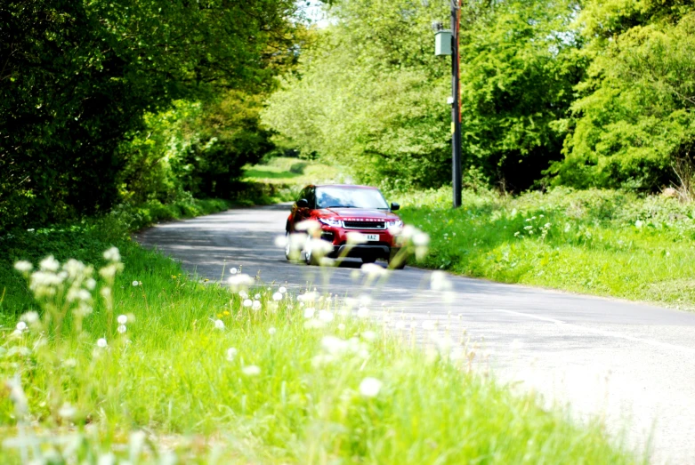 red car driving along road in country area