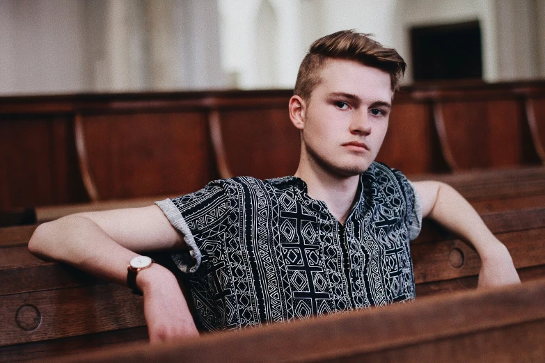 young man sitting alone in a church with wooden pews