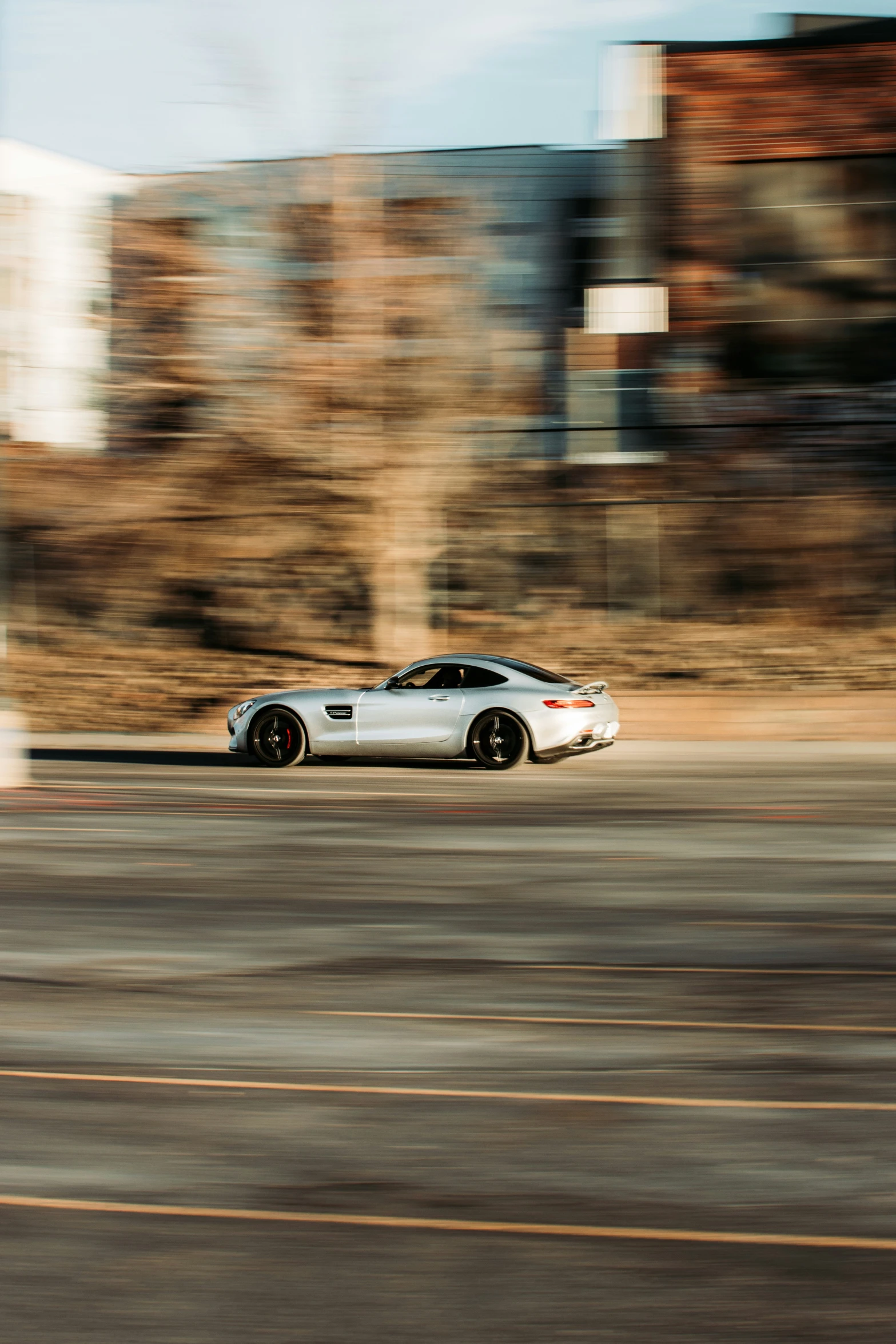 a sports car driving down a road in the day